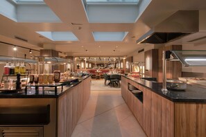 A modern kitchen with skylights, a central island, and a dining area in the background.