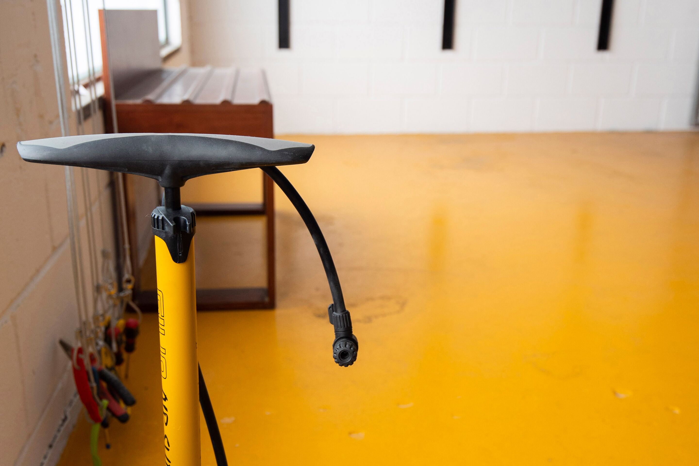 A yellow bicycle with a black seat and handlebar, a black cable, and a yellow floor.