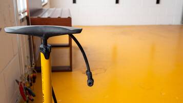 A yellow bicycle with a black seat and handlebar, a black cable, and a yellow floor.