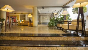 A hotel lobby with a marble floor, two sofas, and a reception desk.
