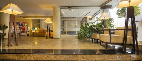 Un vestíbulo de hotel con piso de mármol, dos sofás y una mesa de recepción.