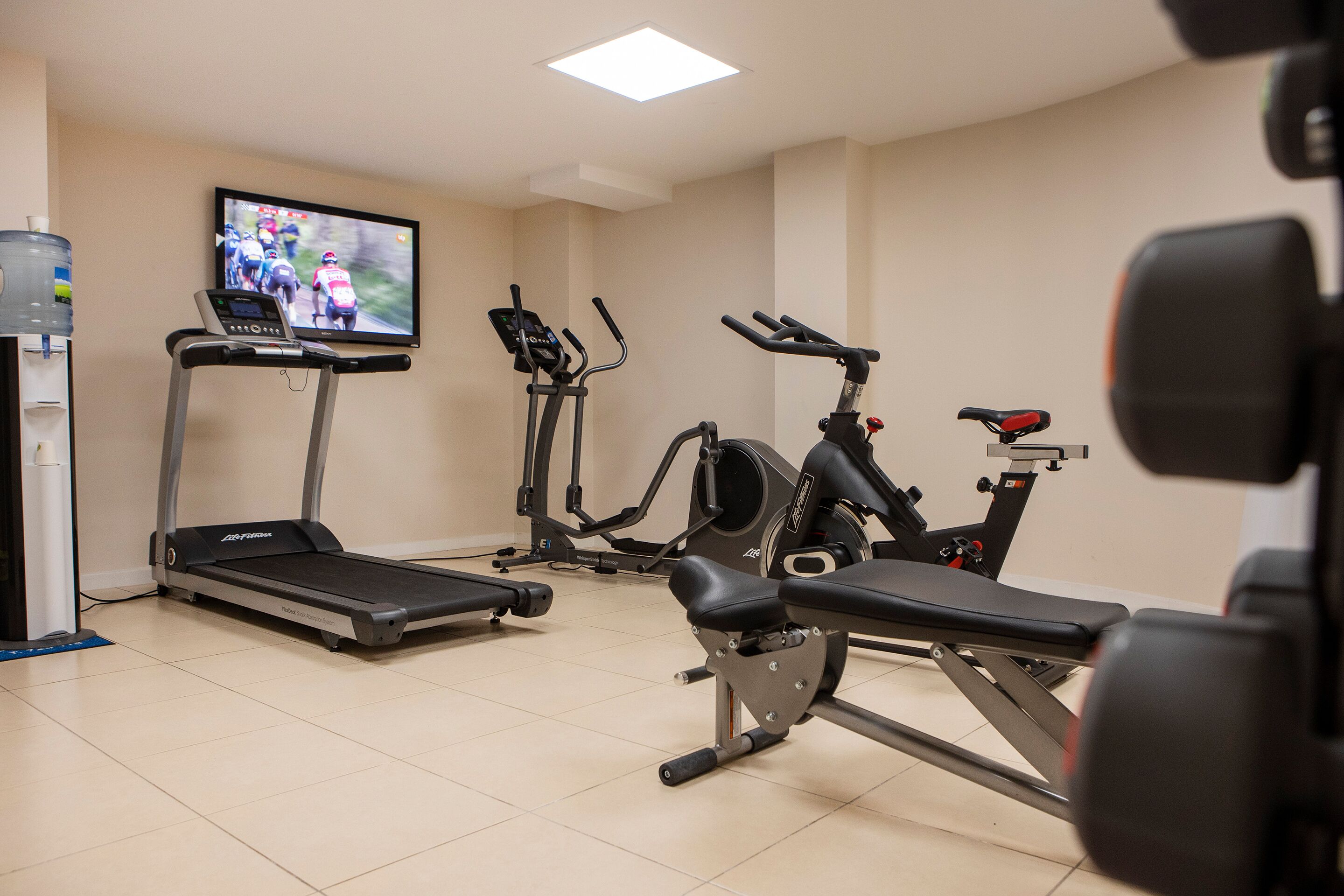 A gym with treadmills, an elliptical, and a bench.