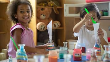Two children engaged in a science experiment with colorful liquids in bottles.