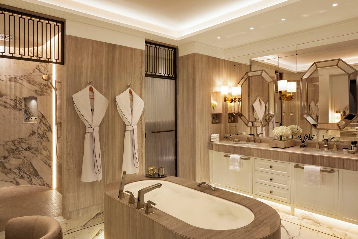 A modern bathroom with a freestanding bathtub, wooden vanity, and a large mirror.