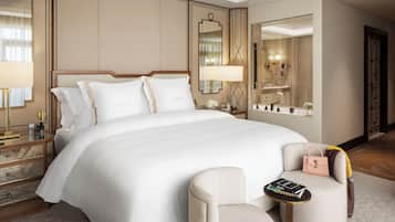 Ein Hotelzimmer mit einem großen Bett, Nachttischen, einem Sessel, einem kleinen Tisch mit Büchern und einem Spiegel.