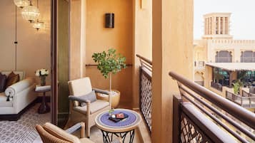 Un balcon agrémenté de meubles en osier, d’une plante en pot et offrant une vue sur des bâtiments traditionnels.