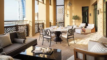 Un espace extérieur ensoleillé, aménagé avec des meubles de jardin, où une table est dressée pour le thé, entourée de canapés et de fauteuils.