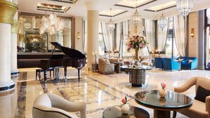 Un vestíbulo imponente con un piano de cola, asientos lujosos y una decoración elegante.