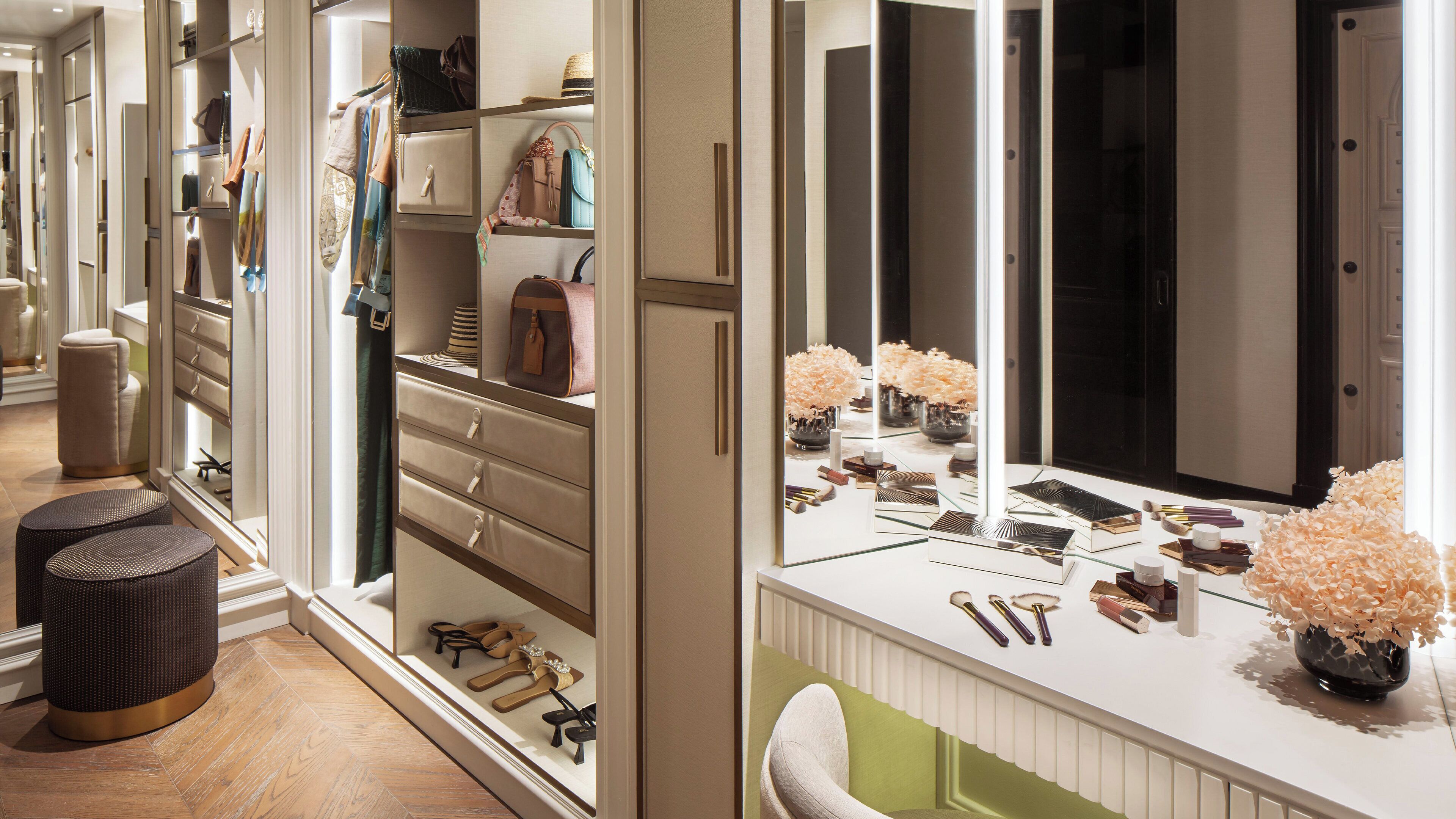 Un tocador bien organizado con un espejo grande, productos de maquillaje y un jarrón con flores.