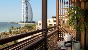 Un balcón con vistas al hotel Burj Al Arab, palmeras y una planta en maceta.
