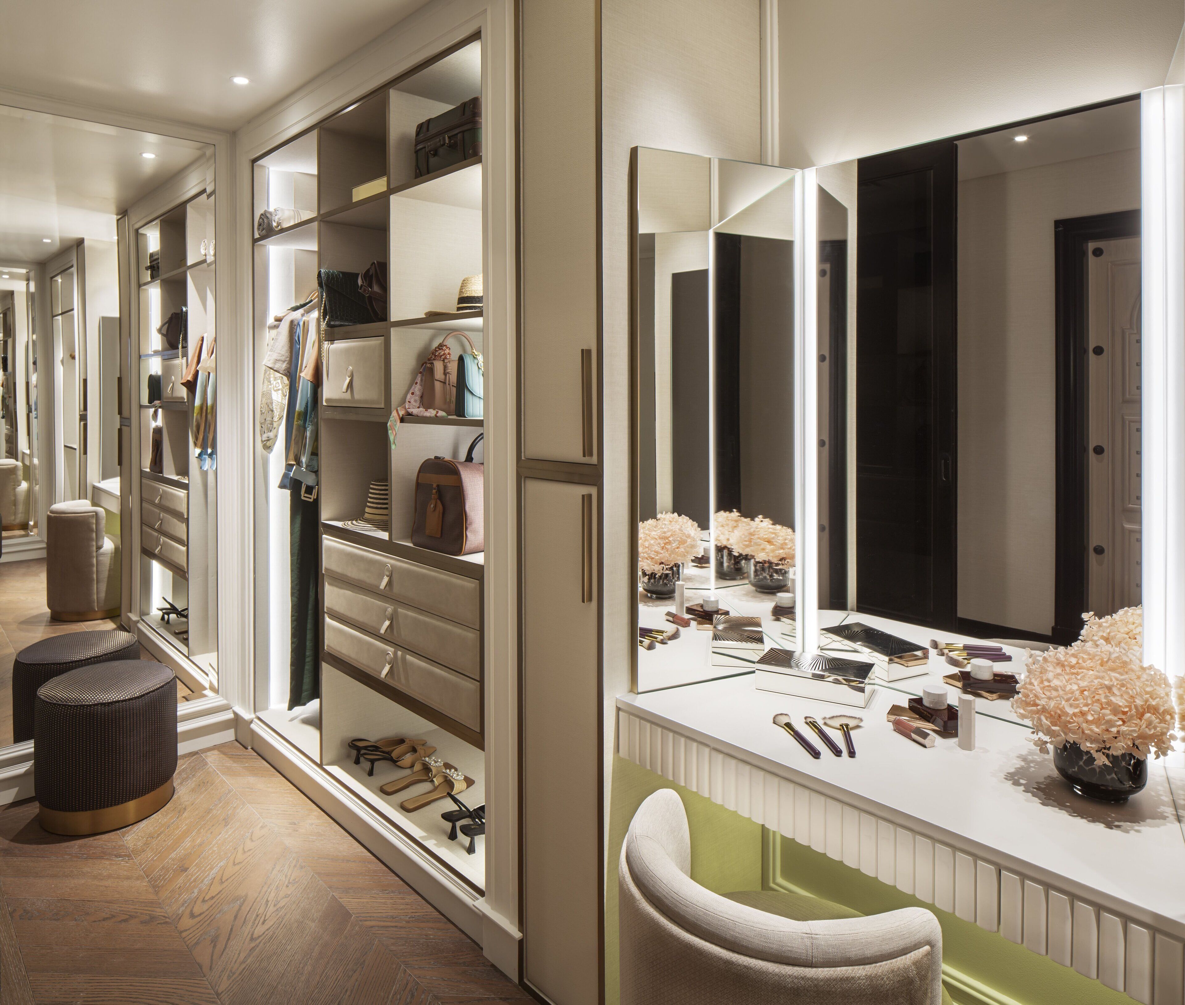 Un dressing avec de nombreuses étagères et tiroirs, une coiffeuse dotée d’un grand miroir et un petit tabouret.