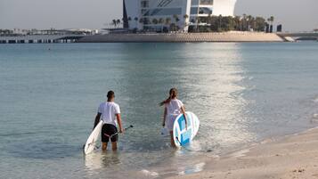 Dos personas caminando hacia la playa con tablas de surf.