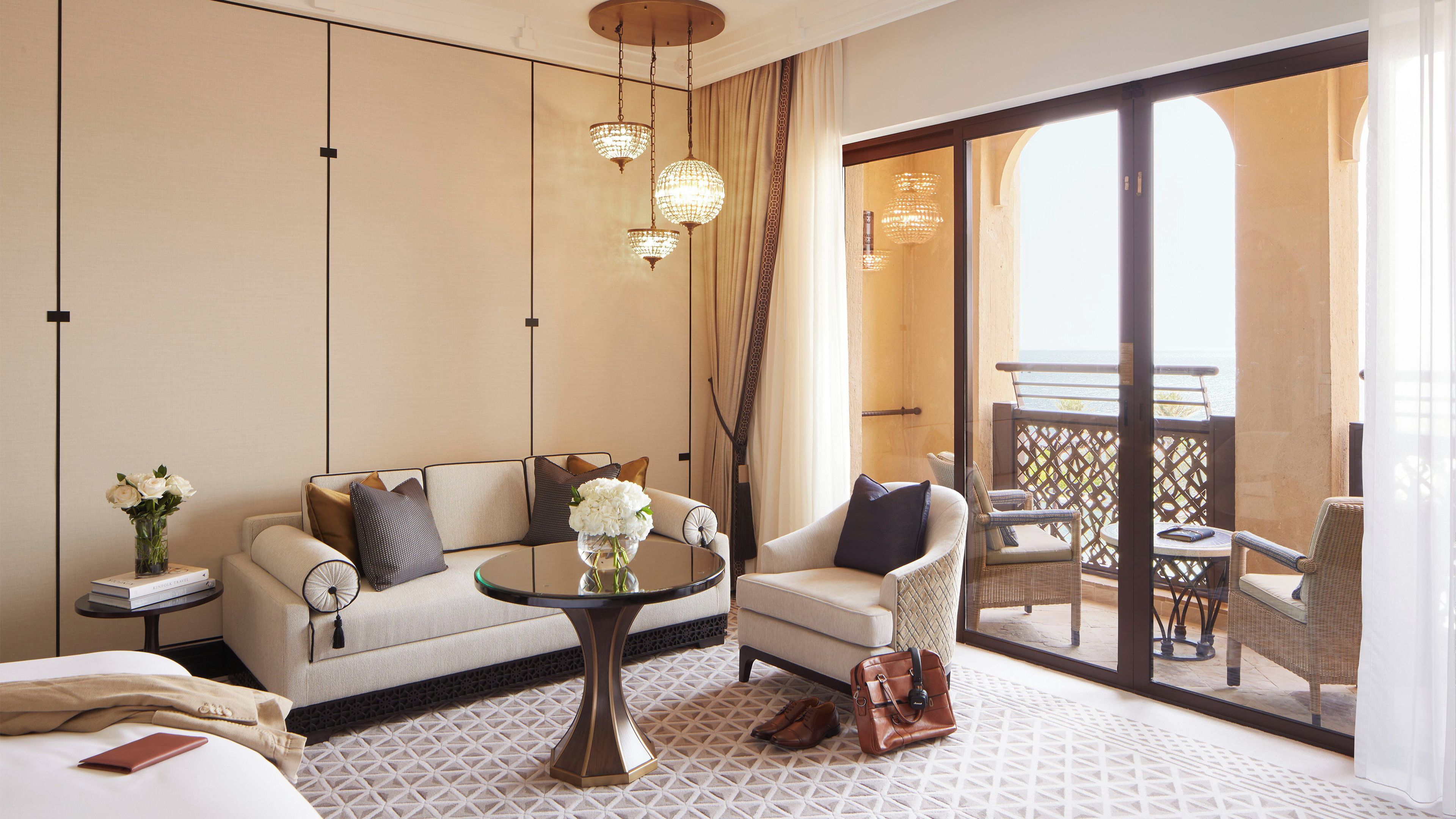 Ein Hotelzimmer mit einer Couch, einem Sessel und einem Balkon mit Blick.