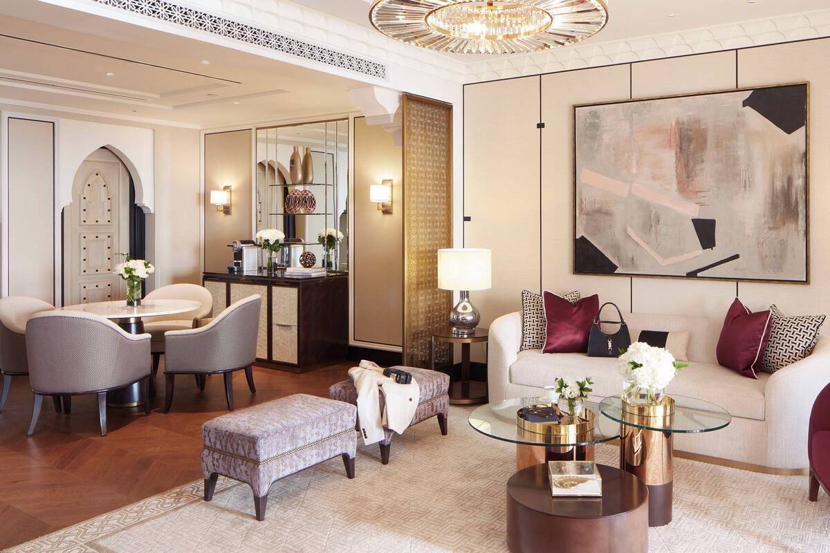 A spacious living room with a round coffee table, a sofa, a dining area with a table and chairs, and a large abstract painting on the wall.