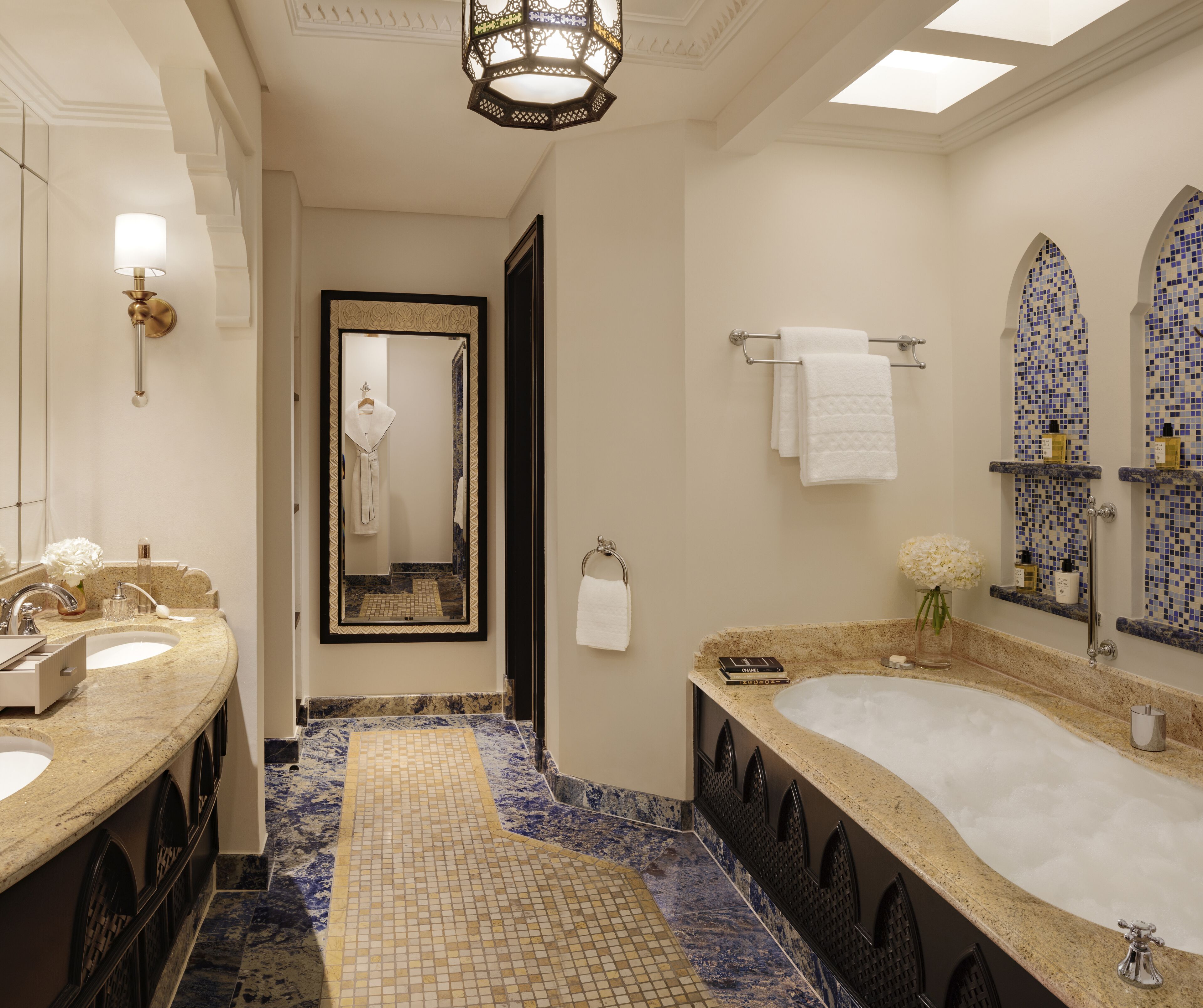 Une salle de bain luxueuse avec une grande baignoire, deux lavabos, un miroir et un sol carrelé.