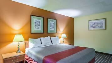 Habitació d'hotel amb un llit, dues làmpades de nit, una tauleta de nit i tres quadres penjats a la paret.