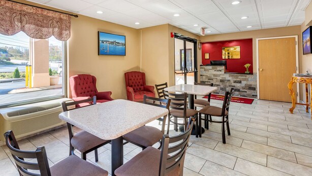 A hotel dining area with tables and chairs, a red wall with a fireplace, and a view of the outside. - Econo Lodge Lookout Mountain (Chattanooga)