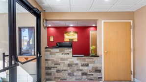 A reception area with a red wall, a stone wall, a wooden door, and a red carpet with the EconoLodge logo. - Econo Lodge Lookout Mountain (Chattanooga)