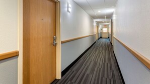 A hotel hallway with wooden doors, carpeted floors, and light-colored walls. - Econo Lodge Lookout Mountain (Chattanooga)