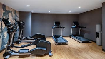 Un gimnasio con cintas de correr, elípticas y una bicicleta estática.