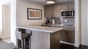 Una cocina moderna con barra, electrodomésticos de acero inoxidable y salpicadero gris.