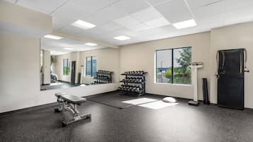A gym with exercise equipment, a mirrored wall, and a window with a view.