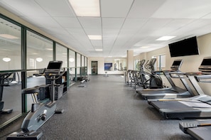 A gym with treadmills, exercise bikes, and a mirrored wall.