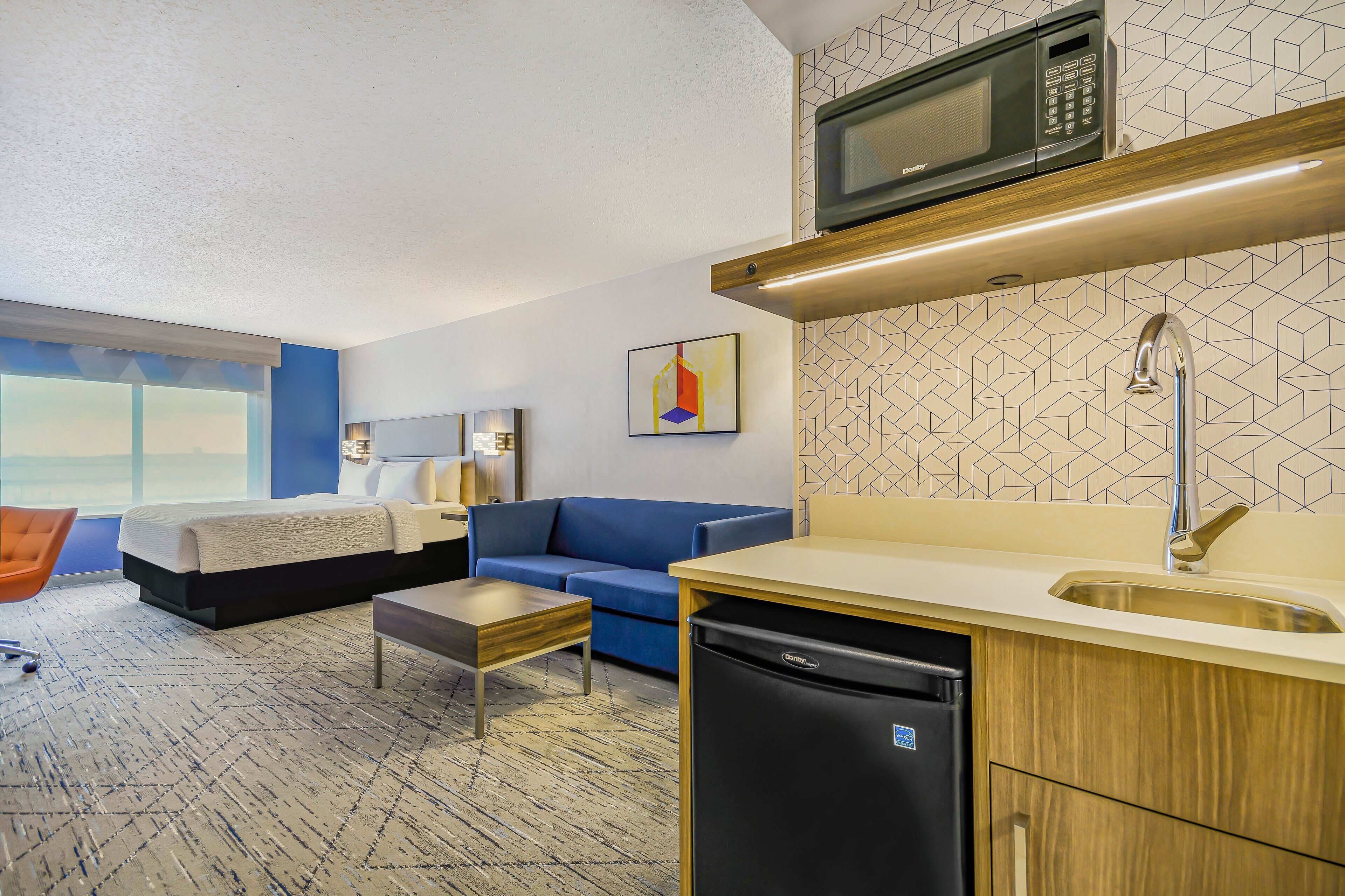 Une chambre d’hôtel compacte comprenant un lit, un canapé, une kitchenette et un petit coin repas.