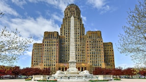 A large, historic building with a central monument, surrounded by a landscaped area with trees and a fountain. - Holiday Inn Express Hotel & Suites Buffalo-Airport by IHG (Buffalo)