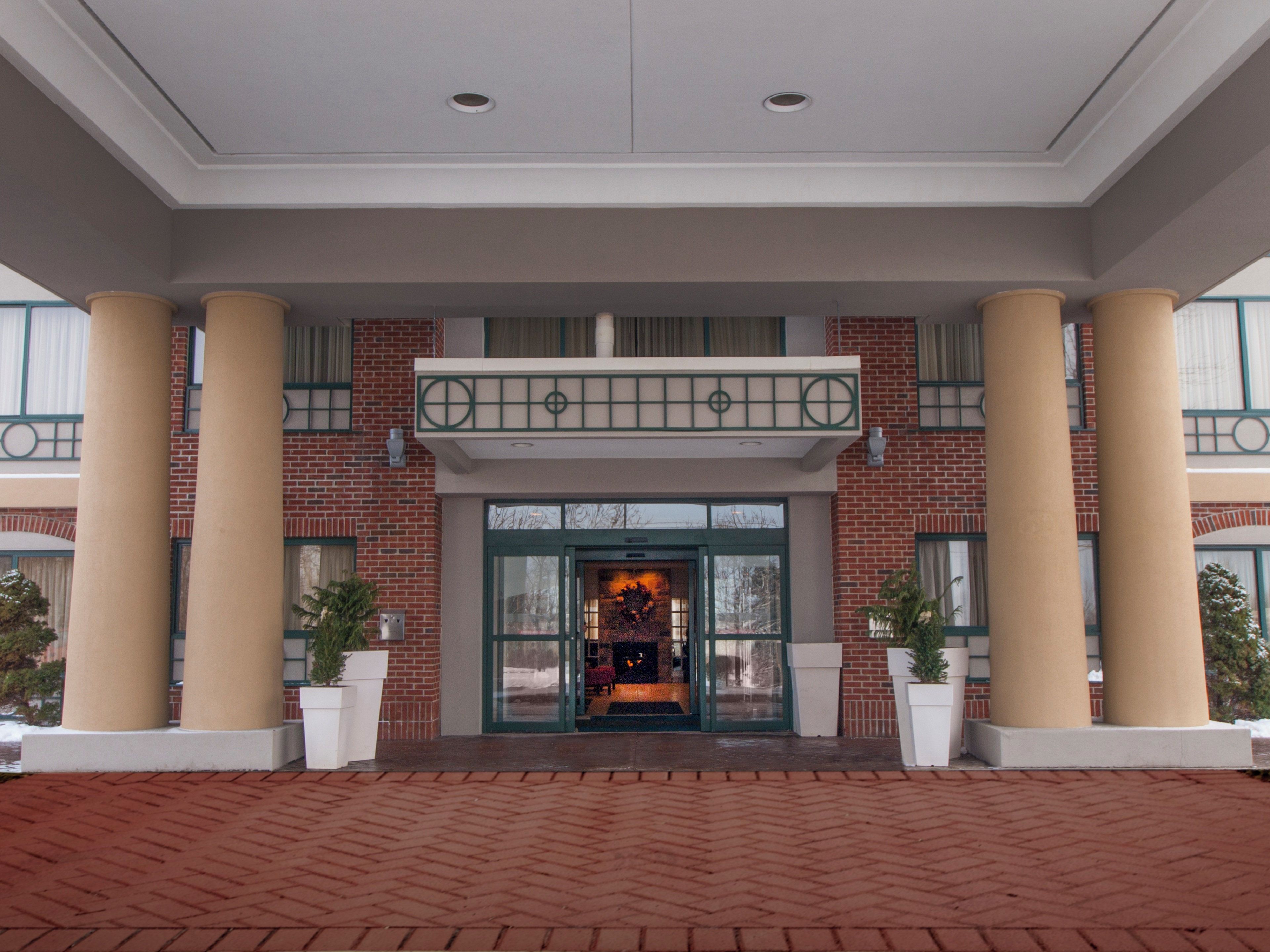 A hotel entrance with a brick facade, large columns, and a glass door entrance.