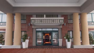 A hotel entrance with a brick facade, large columns, and a glass door entrance.