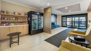 A lobby area with a vending machine, snack shelves, seating, and a reception desk. - Holiday Inn Express Hotel & Suites Buffalo-Airport by IHG (Buffalo)