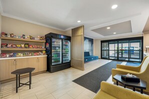 A lobby area with a vending machine, snack shelves, seating, and a reception desk.