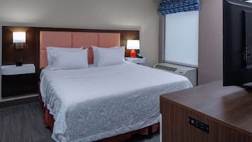 Habitación de hotel con una cama grande, dos mesitas de noche con lámparas, un televisor de pantalla plana y una ventana con vistas.