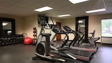 A gym with treadmills, dumbbells, and a red exercise ball.