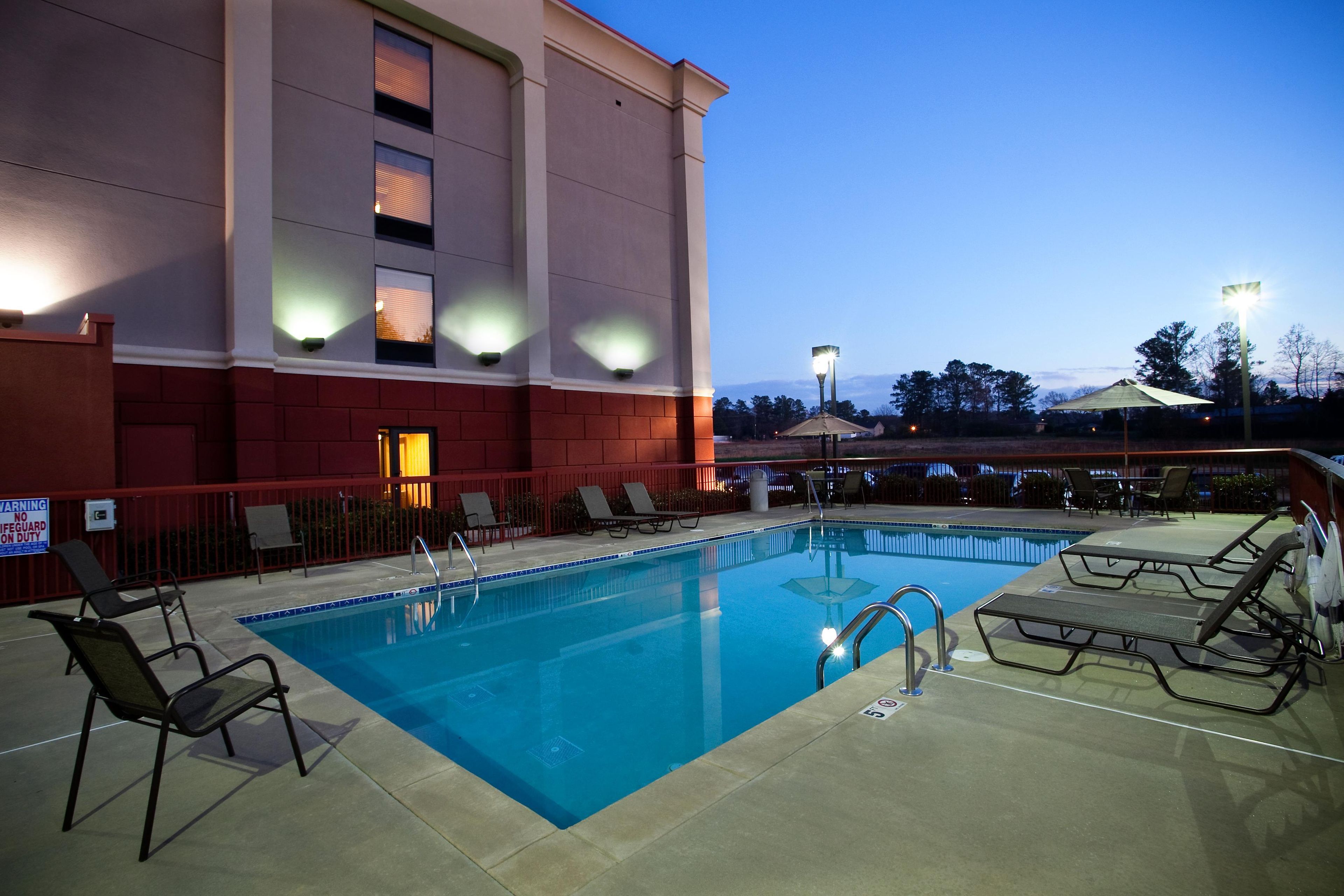 A swimming pool with lounge chairs and a building in the background.
