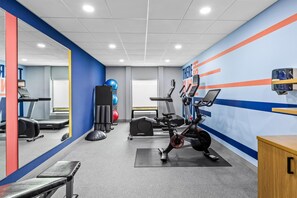 A gym with exercise equipment, a mirrored wall, and a motivational poster.