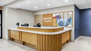A reception desk with a 'Welcome to Hampton' sign, a digital kiosk, and a wooden counter. - Hampton Inn Carrollton (Carrollton)