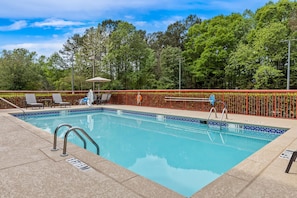 A rectangular swimming pool with a tiled edge, surrounded by a red fence, and equipped with a ladder. - Hampton Inn Carrollton (Carrollton)