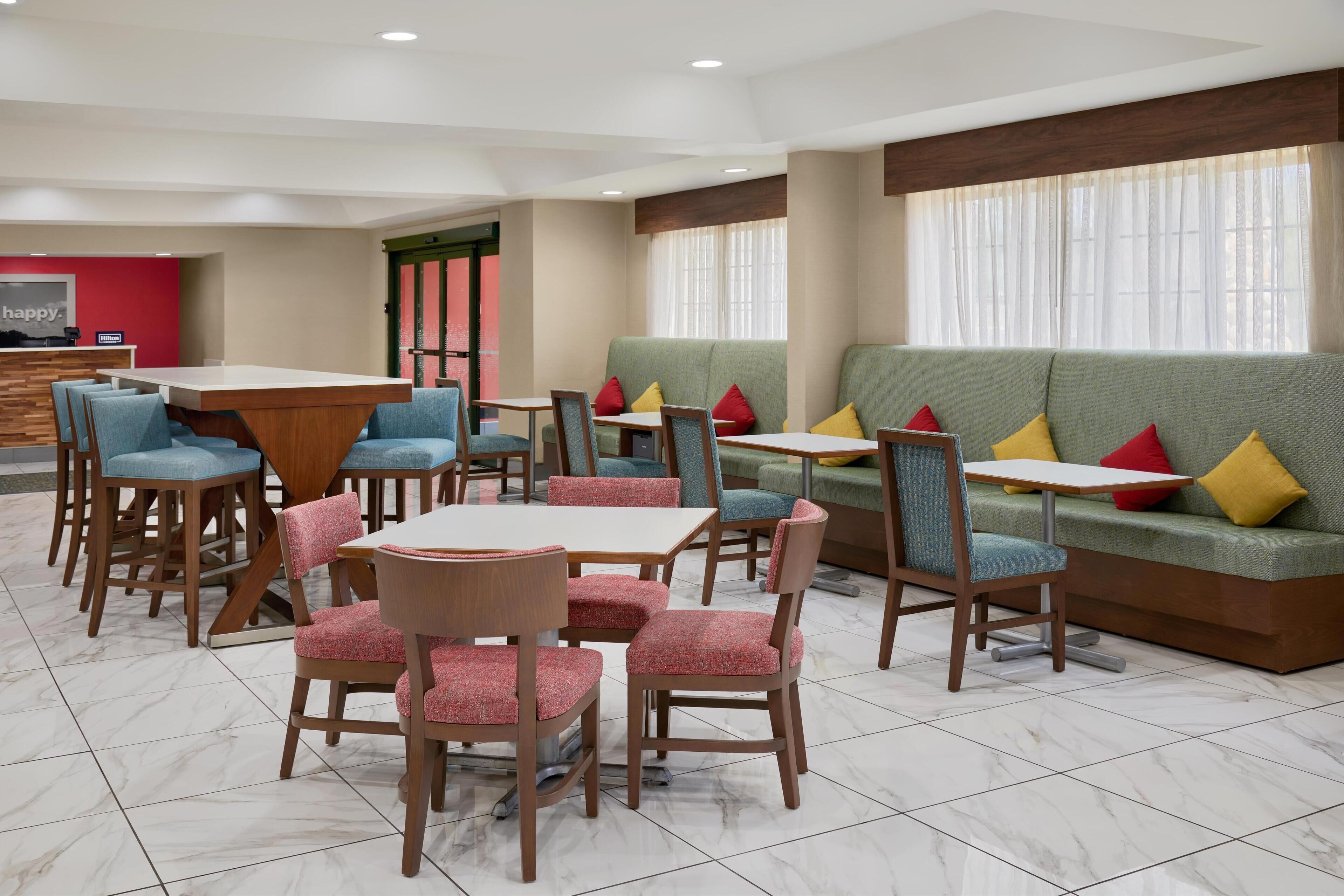 A hotel lobby with a reception desk, seating area with couches and chairs, and a tiled floor.