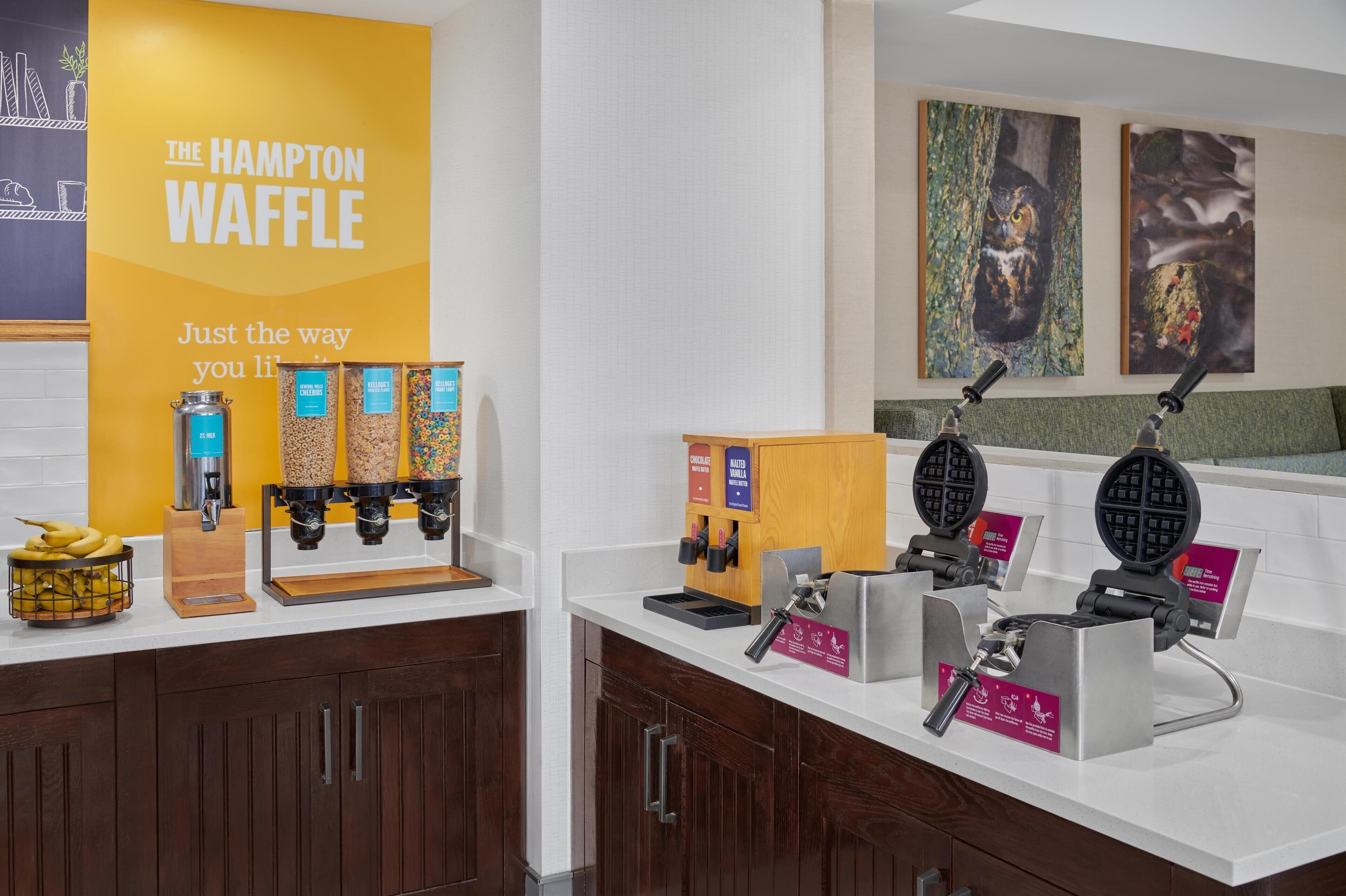 A kitchen area with waffle makers, a display of waffles, and a sign for The Hampton Waffle.
