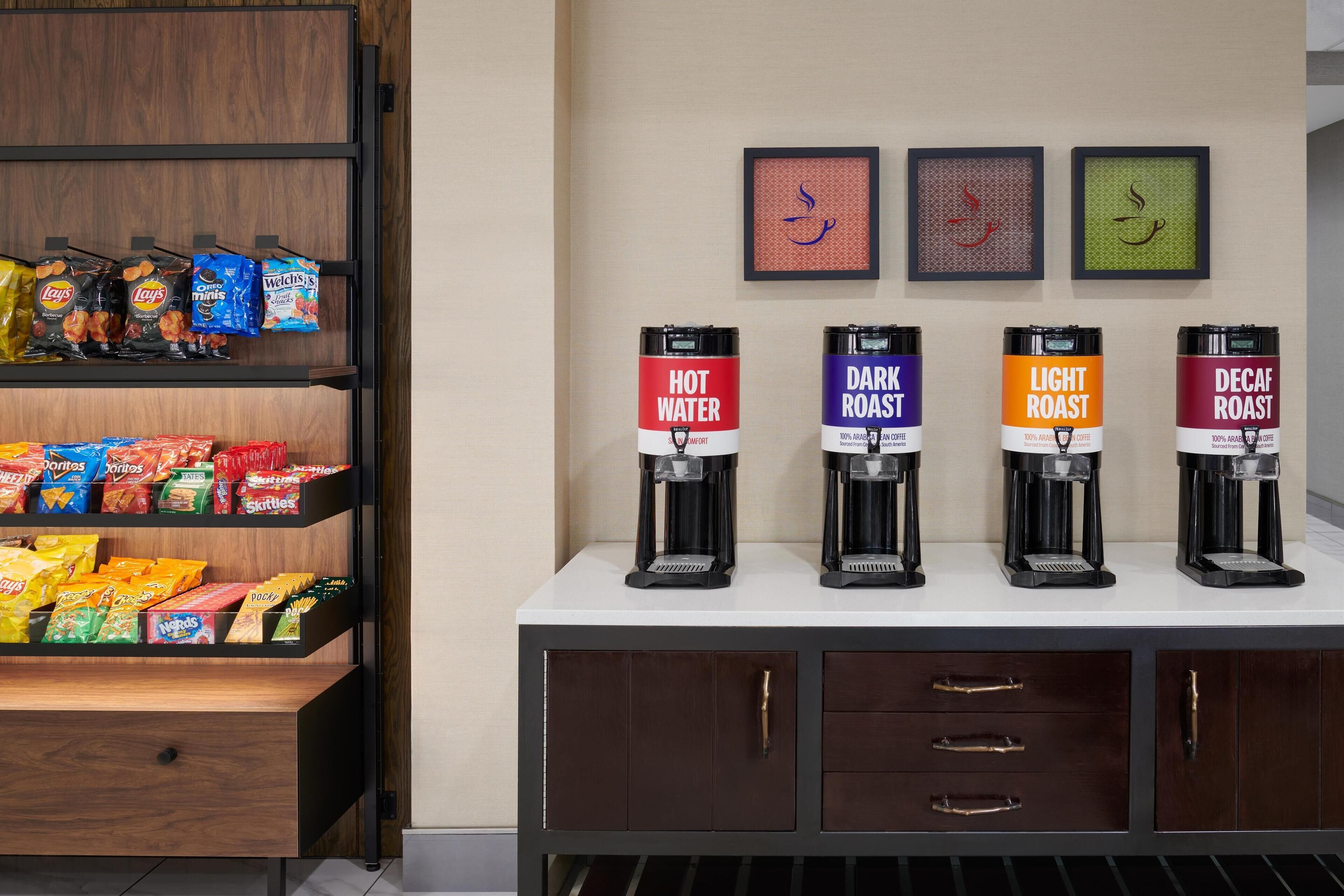 A coffee station with four coffee dispensers labeled 'Hot Water,' 'Dark Roast,' 'Light Roast,' and 'Decaf Roast.'