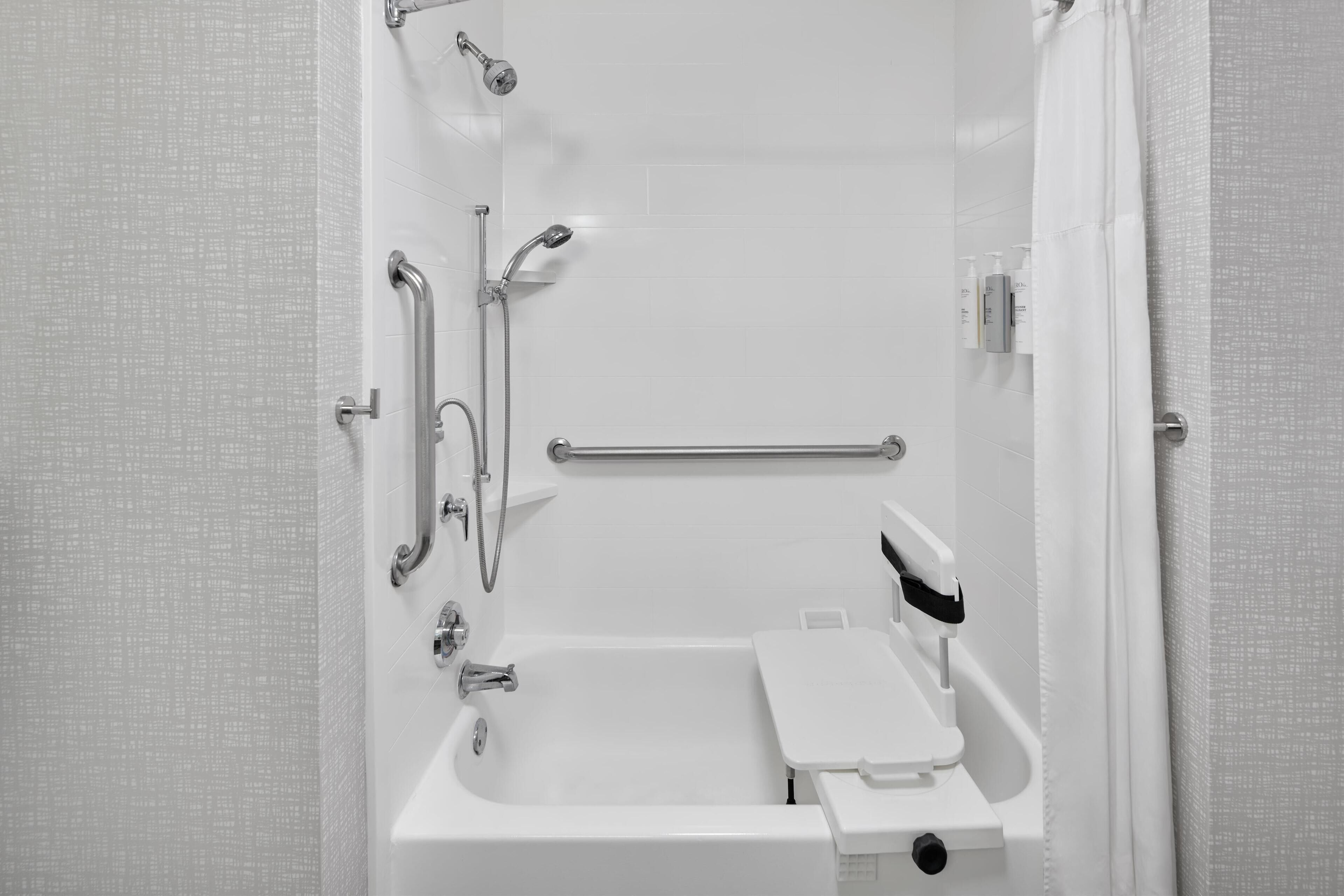 A modern bathroom with a walk-in shower, grab bars, and a handheld showerhead.