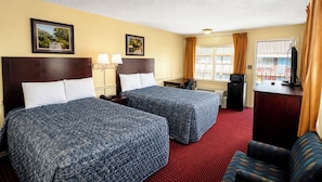 A hotel room with two beds, a desk, a television, and a window with curtains. - Capt. John Smith Inn (Williamsburg)