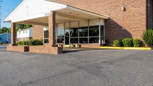 A brick building with a covered entrance, numbered 2225, and a parking lot in front. - Capt. John Smith Inn (Williamsburg)