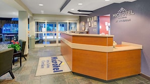 A reception area with a wooden reception desk, a check-in counter, and a wall with the Microtel logo.