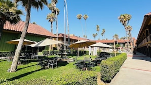 A resort courtyard with palm trees, outdoor seating, and a fountain. - Hotel Saddleback Los Angeles - Norwalk (Norwalk)