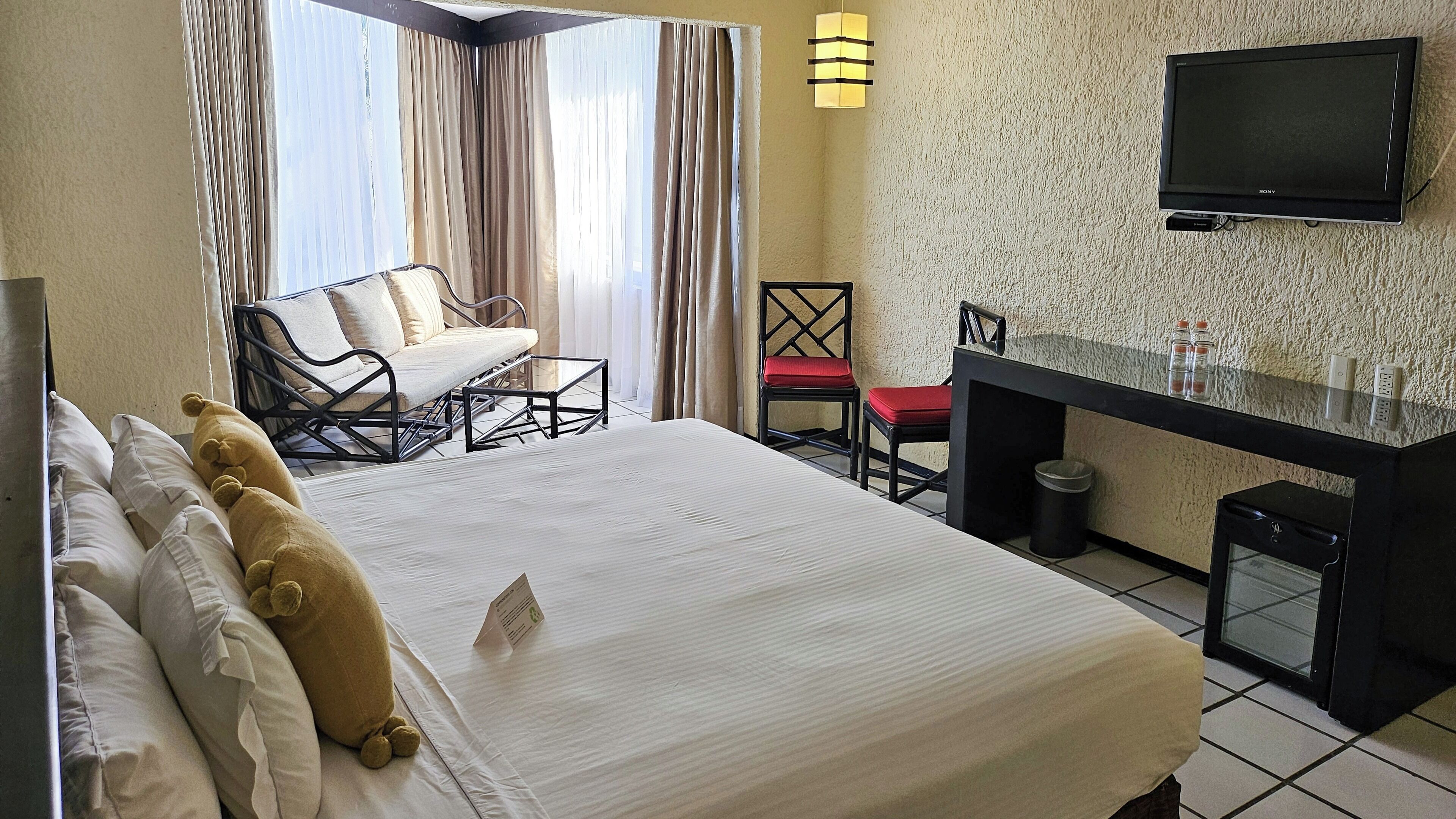 A hotel room with a bed, a desk, a chair, and a television.