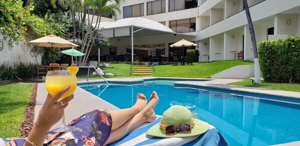 A poolside area with lounge chairs, umbrellas, and a person relaxing with a drink. - Casa Francisco Cuernavaca (Cuernavaca)