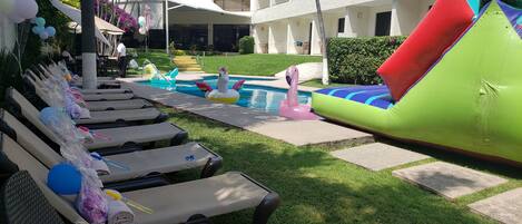 A pool area with lounge chairs, inflatable toys, and a pool.